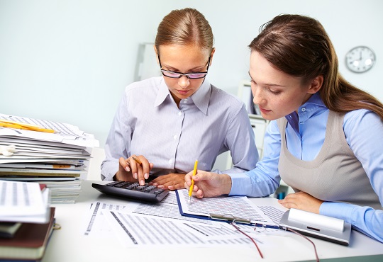 Concentrated business women reviewing accounting report